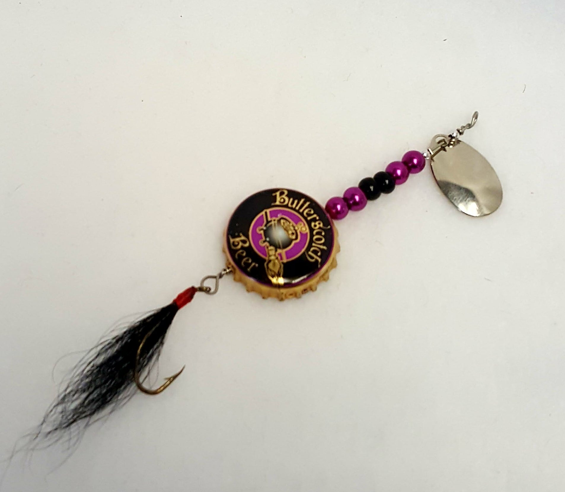 Lure has a black bottle cap with a cauldron, black & purple beads, and black fly.
