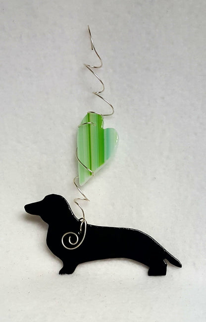 This dachshund has a rich black color and is suspended under a striped green heart. Suncatcher hangs 6.5 inches.