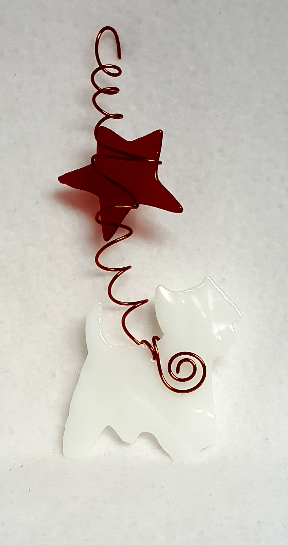 The West Highland terrier has a handsome white coat and stands beneath a bright red star. Suncatcher hangs 7 inches.